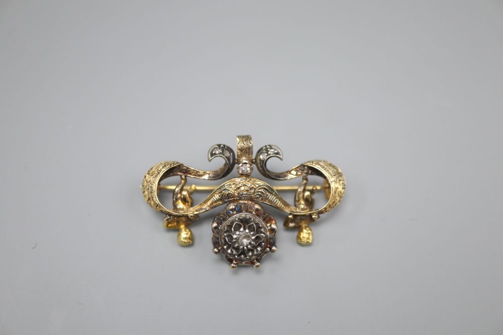 An ornate Victorian diamond set gold and silver suspension brooch, with central cluster flanked by putti holding a scroll, width 4.5cm,